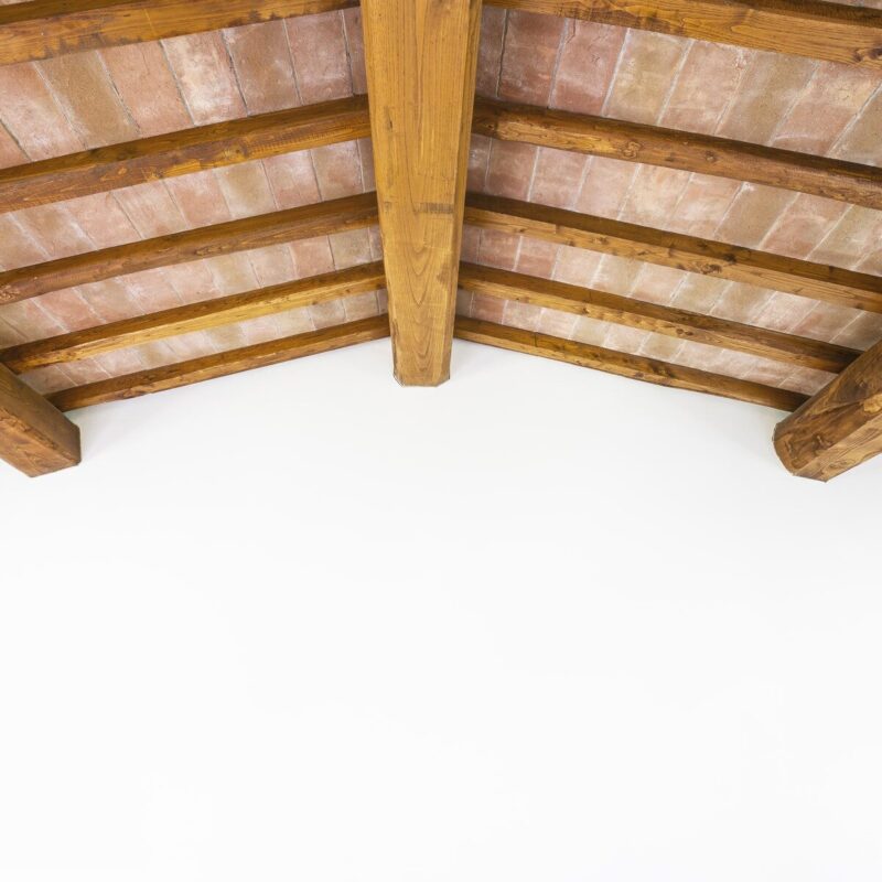 Tuscan traditional wood beam ceiling, red bricks and white wall. Italy